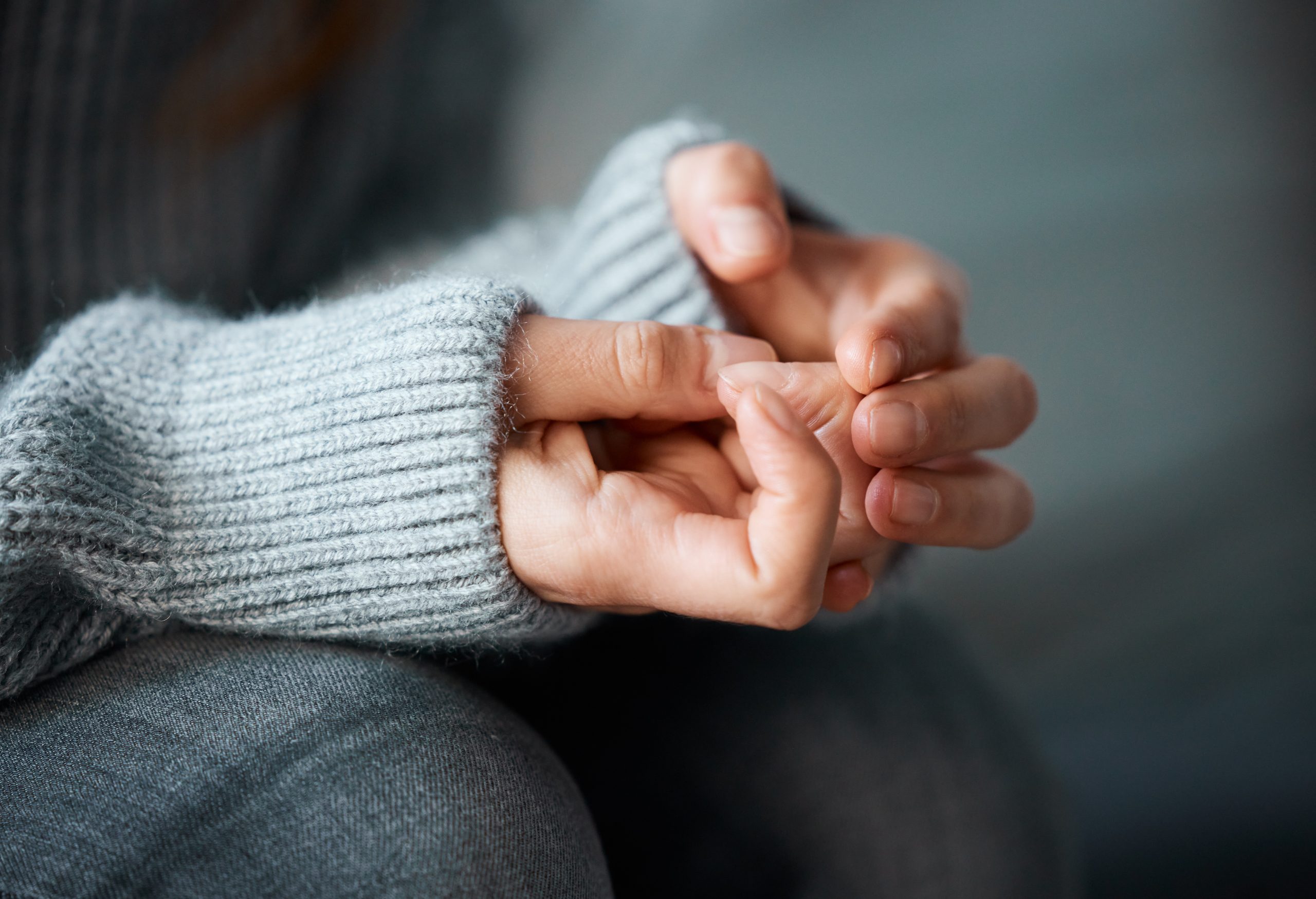 Shot of a woman nervously clasping her hands together.